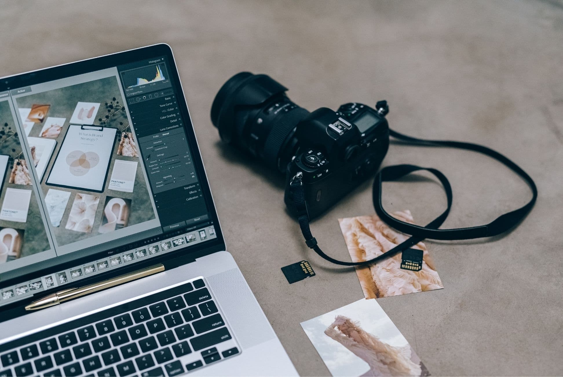Laptop with a brand mood-board beside a camera and printed photos